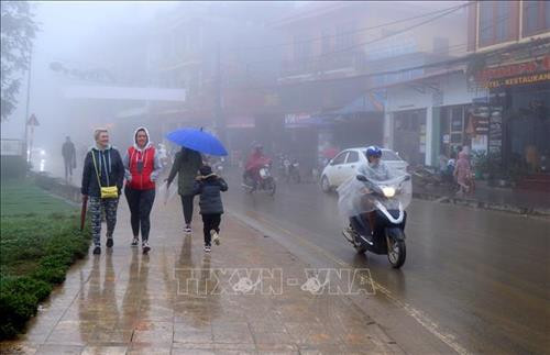 Du khách nước ngoài du lịch Sa Pa trong sương mù và giá lạnh. Ảnh: Quốc Khánh – TTXVN