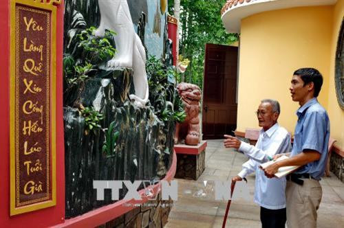 Ông Nguyễn Văn Khỏe, thành viên trong Ban Quản lý Di tích lịch sử Đình Tân Thông giới thiệu với phóng viên TTXVN về câu đối do cố Thủ tướng Phan Văn Khải ghi tặng. Ảnh: Thế Anh - TTXVN