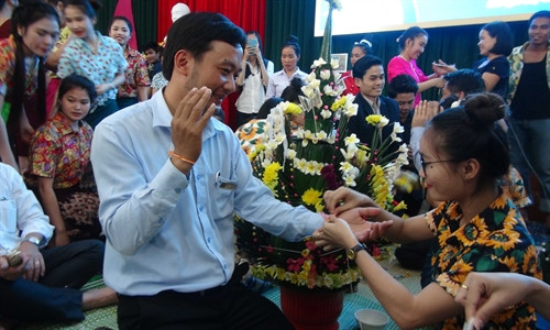 Các bạn lưu học sinh Lào buộc chỉ vào cổ tay cầu may mắn cho các vị khách.