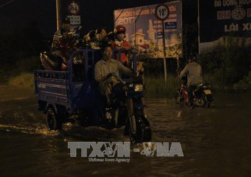 Xe ba gác làm dịch vụ vận chuyển xe máy qua đoạn ngập nước tại huyện Nhà Bè. Ảnh: Xuân Dự - TTXVN