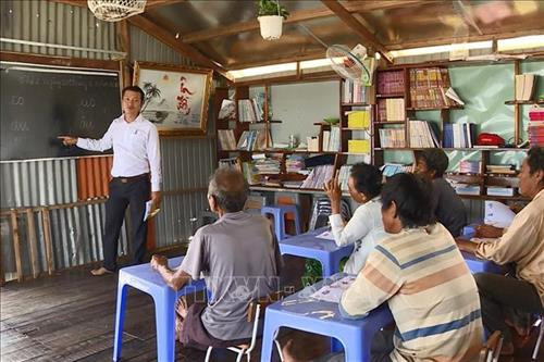 Anh Nguyễn Hoàng Nam trong giờ đứng lớp dạy chữ cho những người Việt kiều Campuchia lớn tuổi trên lòng hồ Trị An. Ảnh: Lê Xuân-TTXVN