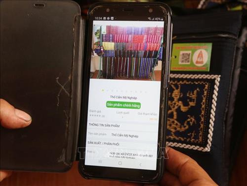 Sử dụng ứng dụng trên điện thoại di động soi quét vào mã tem dán trên sản phẩm thổ cẩm để truy xuất nguồn gốc hàng hóa. Ảnh: Nguyễn Thành - TTXVN