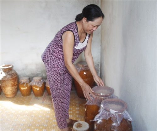 Bà H’Ben kiểm tra các ché rượu cần đang ủ Bà H’Ben kiểm tra các ché rượu cần đang ủ