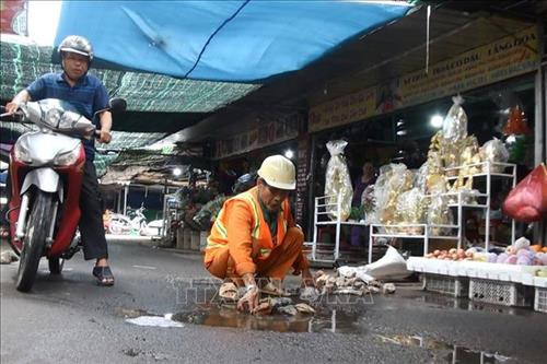 Ông Võ Văn Có đang vá những ổ gà trên đường vào chợ Gia Canh. Ảnh: Lê Xuân-TTXVN Ông Võ Văn Có đang vá những ổ gà trên đường vào chợ Gia Canh. Ảnh: Lê Xuân-TTXVN