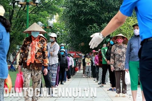 Người dân xếp hàng nhận gạo đúng khoảng cách và tuân thủ hướng dẫn của tình nguyện viên tại Nhà Văn hóa Nghĩa Tân, quận Cầu Giấy, Hà Nội.