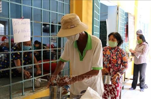 Những người bán vé số có hoàn cảnh khó khăn nhận suất cơm miễn phí tại bếp ăn. Ảnh: Chương Đài - TTXVN