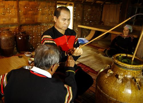 Thầy cúng cầm vòng đồng đeo trên tay gia chủ và đọc lời khấn cầu sức khỏe, nhắc lại lời hẹn. Ảnh: H.H