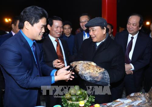 Thủ tướng Nguyễn Xuân Phúc xem và nghe giới thiệu về sản phẩm tiêu biểu của tỉnh Hà Giang. Ảnh: Thống Nhất –TTXVN