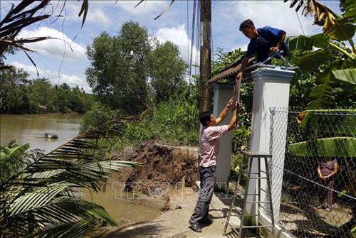 Sạt lở làm mất đường đi và ăn sâu vào sát cổng nhà dân. Ảnh: Thanh Liêm – TTXVN