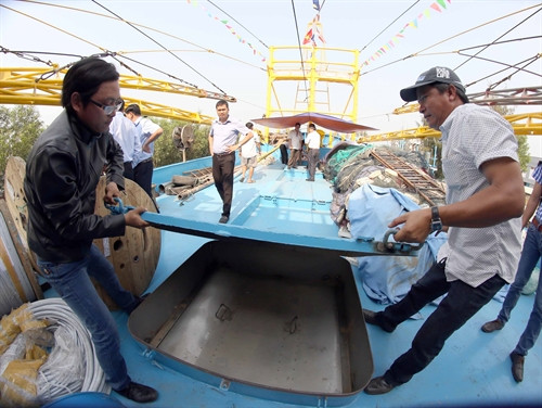 Ngư dân Trần Văn Mười (bên phải) chủ tàu cá vỏ thép ĐNa – 90777 TS đang kiểm tra hầm chứa thủy sản trước giờ hạ thủy.