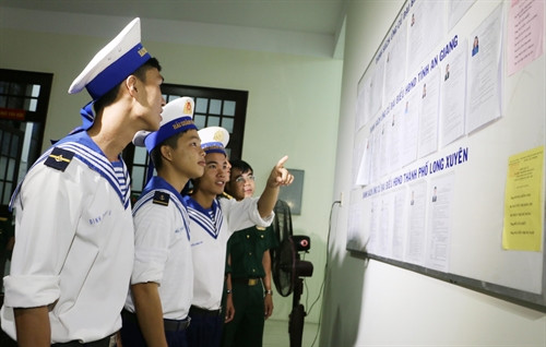 Các chiến sỹ hải quân ở thành phố Long Xuyên (An Giang) nghiên cứu tiểu sử các ứng cử viên trước khi bỏ phiếu. Ảnh: Công Mạo – TTXVN