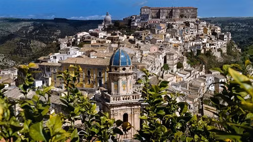 Trong phim "Bố già" của nhà văn Mario Puzo, thị trấn Modica ở vùng Sicily là quê hương của nhân vật ông trùm mafia Vito Corleone. Ảnh: Pinimg. Du khách đến thị trấn thường ăn bánh quy ngọt và uống Granitas tại quán bar Vitelli, nơi nhân vật Michael Corleone từng ngồi, khi về quê cha để lẩn trốn sự truy đuổi. Ảnh: James Dunn/Daily Mail. Quán bar trong phim và ngoài đời thực không có sự khác biệt, bên ngoài được phủ xanh bằng giàn cây leo. Ảnh: Shutterstock/Goran Vrhovac. Một cảnh trong phim "Bố già". Trong phim, Michael Corleone cùng các bạn của mình đến quán bar để xin cưới con gái chủ quán, người anh đã yêu ngay lần đầu gặp trên một con đường làng. Ảnh: Paramount Pictures/REX/Shutterstock. Từ bar Vitelli, du khách có thể nhìn thấy nhà thờ Savoca, nơi đạo diễn Francis Ford Coppola quay cảnh đám cưới của Michael Corleone và người vợ đầu tiên. Ảnh: Shutterstock/Anadman BVBA. Nhờ những cảnh quay trong bộ phim huyền thoại, Sicily trở thành thỏi nam châm thu hút du khách từ khắp nơi trên thế giới đổ về. Ảnh: James Dunn/Daily Mail. Nhiều du khách thích thú khi được thuê lái những chiếc xe hơi cổ đến núi Etna, ngọn núi lửa nổi tiếng của hòn đảo và ghé thăm những vườn nho trong vùng. Ảnh: James Dunn/Daily Mail. Người dân Sicily ưu ái dành tình cảm cho đạo diễn Francis Ford Coppola bằng một bức tượng kim loại hình ông bên máy quay phim. Phía xa là nhà thờ Santa Maria Degli Angeli, nơi quay cảnh ông trùm Michael Corleone kết hôn với người vợ đầu tiên. Ảnh: James Dunn/Daily Mail. Cảnh quan vùng Sicily giữ được nét trầm mặc, yên tĩnh và có phần bí hiểm, giống như những gì đã xuất hiện trên phim cách đây hơn 40 năm. Ảnh: Shutterstock/Nikiforov Alexander. Một địa điểm nổi tiếng khác ở Sicily là nơi nhân vật Vito Corleone sinh ra, xuất hiện trong "Bố già" phần III. Ảnh: James Dunn/Daily Mail. Ngoài khu nội thất sang trọng, bên ngoài biệt thự là khu vực ăn uống mở. Du khách có thể thưởng thức rượu vang và món ăn ngon của địa phương vào những buổi chiều nắng nóng. Ảnh: James Dunn/Daily Mail. Không gian mở hướng ra biển mang lại cảm giác thư giãn yên tĩnh. Ảnh: James Dunn/Daily Mail. Sau chuyến thăm các địa danh xuất hiện trong phim, du khách có thể ghé một nhà hát cổ tuyệt đẹp nằm trên quả đồi nhỏ nhìn ra vịnh. Ảnh: Shutterstock/Arts lllustrated Studios.