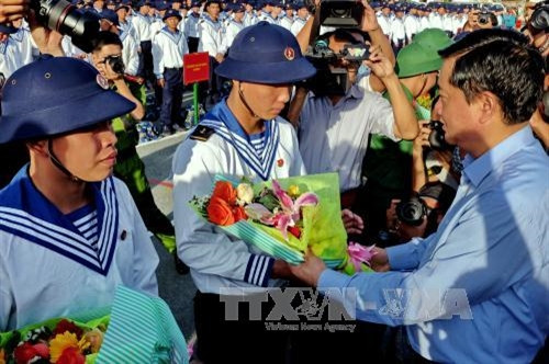 Bí thư Thành ủy Đinh La Thăng tặng hoa chúc mừng và động viên các thanh niên trúng tuyển NVQS tại điểm giao quân Quận 9, Thành phố Hồ Chí Minh. Ảnh: Thế Anh - TTXVN