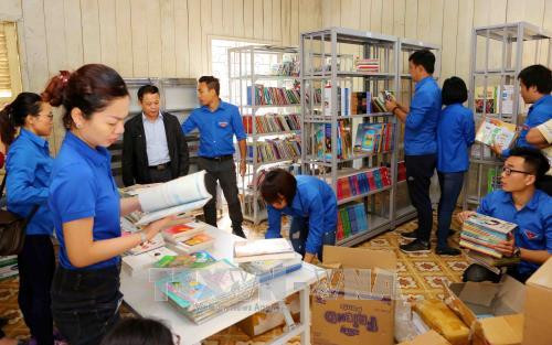 Đoàn viên thanh niên TTXVN chuyển sách lên giá tại thư viện trường Phổ thông Dân tộc bán trú Tiểu học và THCS Phình Hồ (xã Phình Hồ, huyện Văn Chấn). Ảnh: Thành Đạt – TTXVN