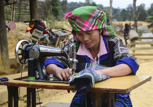 Một phụ nữ người Mông đang hoàn thiện những đường chỉ cuối cùng cho bộ trang phục mừng năm mới.