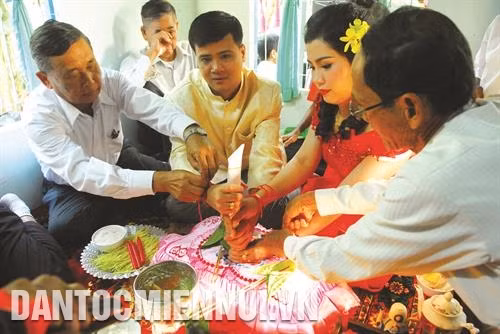 Hai bên gia đình thực hiện “cột chỉ tay” cho cô dâu và chú rể. Phía họ nhà trai buộc tay phải của cô dâu còn phía họ nhà gái buộc tay trái của chú rể.