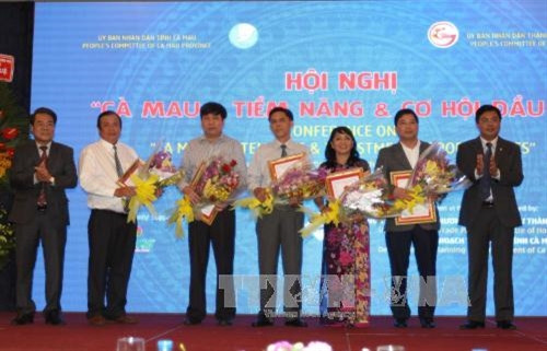 Bí thư Tỉnh ủy tỉnh Cà Mau Dương Thanh Bình và Chủ tịch UBND tỉnh Cà Mau Nguyễn Tiến Hải trao quyết định chủ đầu tư, và giấy chứng nhận đầu tư cho các doanh nghiệp tại hội nghị. Ảnh: Thanh Vũ-TTXVN