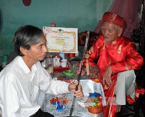 Nghệ nhân Lữ Hữu Thi (bên phải), truyền những ngón nghề cho người con trai của mình là ông Lữ Viết Minh. Ảnh: Quốc Việt - TTXVN