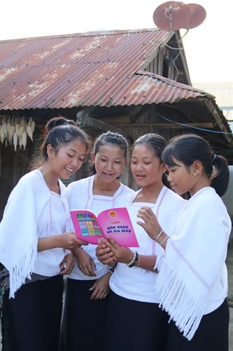 Các thiếu nữ dân tộc Chu Ru trong độ tuổi từ 13 đến 16 tiếp cận với tài liệu tuyền truyền về Luật hôn nhân và gia đình. Ảnh: Nam Sương - TTXVN