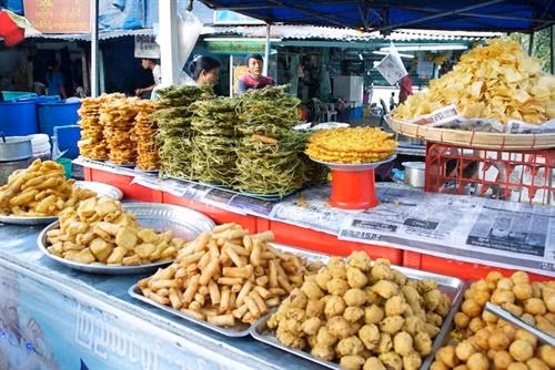 Salad lá trà: Một trong những đặc sản nổi tiếng của Myanmar là lephet hay lá trà lên men. Chúng được ăn riêng hoặc dùng làm nguyên liệu cho món lephet thoke - salad lá trà muối. Ảnh: MultiVerse Advertising. Các lá trà muối chua chua, đắng được trộn với bắp cải thái sợi, cà chua, đậu rán giòn, các loại hạt, một chút dầu tỏi, ớt và tỏi tươi thái lát. Món này có thể dùng ăn vặt, khai vị hoặc ăn kèm với cơm. Ảnh: Mark Wiens. Cơm người Shan: Món nga htamin (cơm cá) của người Shan gồm cơm được nấu với nghệ nặn thành hình tròn (hoặc dẹt), sau đó cho thêm thịt cá và dầu tỏi lên trên. Cơm thường được ăn kèm với rễ tỏi tây, tỏi tươi và tóp mỡ. Ảnh: Messy Vegetarian Cook. Cà ri Miến Điện: Cà ri là trung tâm của món này, thường được làm từ thịt lợn, cá, tôm, bò hoặc cừu. Tuy nhiên, bạn sẽ có vô số món ăn kèm hấp dẫn. Ảnh: Yourenotfromaroundhere. Cà ri thường được dọn cùng cơm, salad, một đĩa rau xào, một bát canh nhỏ và một đĩa to rau (sống hoặc luộc), rau thơm, cùng nhiều loại sốt chấm. Ảnh: Cambodiatravelforum. Sốt chấm đi kèm có nhiều loại, từ ngapi ye - một loại nước mắm nhạt, tới balachaung - hỗn hợp gia vị khô gồm tỏi, ớt và tôm khô rán giòn. Ảnh: Mark Wiens. Cơm quán trà: Các quán trà của Myanmar không chỉ là nơi bạn giải khát với những cốc trà sữa ngọt ngào. Du khách có thể tận hưởng nhiều món ăn thú vị phù hợp với văn hóa dân tộc của chủ quán. Ảnh: CNN. Bạn có thể gọi các món ăn như mì truyền thống hay htamin thoke - một loại salad trộn cơm. Ảnh: Asiadmc. Các quán trà của người Ấn hoặc người theo đạo Hồi phục vụ nhiều món chịu ảnh hưởng từ ẩm thực của Đông Nam Á, như samosas hay poori (bánh mì rán giòn với cà ri khoai tây) hay bánh mì nướng như nanbya. Ảnh: WanderGuts. Món ăn vặt: Các món ăn vặt ở Myanmar thường được dùng kèm trà vào buổi sáng hoặc chiều. Vị ngọt của chúng không từ đường mà từ các nguyên liệu như cùi dừa, sữa dừa, bột gạo, bột nếp, bột sắn và trái cây. Ảnh: Asiadmc. Những món nổi bật là hsa nwin ma kin (bánh từ bột trộn sữa dừa, bơ ghee và nho khô), bein moun và moun pyit thalet (bánh kếp kiểu Myanmar). Ảnh: Activetravelmagazines. Các món rán: Người Myanmar thích ăn các món rán. Phần lớn các đồ ăn vặt ở vỉa hè hay quán trà là món rán, từ nem, bánh tới bánh mì. Nhiều món mì có rắc thêm akyaw - các thực phẩm rán giòn để trang trí. Ảnh: Myanmar Travel Essentials. Một món rán nổi tiếng đáng thử ở đây là buthi kyaw, bí xanh tẩm bột rán giòn chấm với sốt chua ngọt làm từ me và bột đậu. Ảnh: Midday. Mì đậu phụ người Shan: Món hto-hpu nwe có nghĩa là “đậu phụ nóng” trong tiếng Myanmar. Tuy nhiên, món ăn này không hề có đậu phụ mà gồm một loại cháo đặc làm từ bột đậu. Ảnh: Living + Nomads. Loại sốt dính màu vàng này được rưới lên trên mì sợi nhỏ, thêm thịt gà hoặc thịt lợn được tẩm ướp đậm đà, một ít sa tế. Món này được ăn kèm rau củ muối và nước dùng. Ảnh: Alittleadrift. Nangyi thoke: Đây là một loại mì trộn salad, gồm các sợi mì tròn và dày được trộn với thịt gà, bánh cá, giá trần và trứng luộc. Các nguyên liệu được cho thêm bột đậu rang, nghệ và sa tế, sau đó trộn bằng tay rồi dọn ra ăn cùng dưa muối mà một bát nước dùng. Ảnh: The indolent cook. Mohinga: Mohinga là "món quốc hồn quốc túy không chính thức" của Myanmar. Mì sợi tròn được chan nước dùng làm từ cá và hẹ tây. Món ăn này được bán rong trên đường phố, thường ăn vào bữa sáng hoặc đêm muộn. Bạn có thể cho thêm trứng luộc, akyaw, đậu lentil, chút chanh và bột ớt. Ảnh: Hsaba. Mì người Shan: Sợi mì dẹt và mảnh được chan nước dùng cay, cho thêm thịt lợn hoặc thịt gà, vừng rang và chút dầu tỏi. Món này được ăn cùng rau củ muối. Ảnh: Flavorverse. Mì người Shan có vị tương đối đơn giản, dễ ăn và rất ngon. Mì còn có phiên bản khô được dọn ra với bát nước dùng riêng. Ảnh: Sanctum Inle Resort. Salad lá trà: Một trong những đặc sản nổi tiếng của Myanmar là lephet hay lá trà lên men. Chúng được ăn riêng hoặc dùng làm nguyên liệu cho món lephet thoke - salad lá trà muối. Ảnh: MultiVerse Advertising. Các lá trà muối chua chua, đắng được trộn với bắp cải thái sợi, cà chua, đậu rán giòn, các loại hạt, một chút dầu tỏi, ớt và tỏi tươi thái lát. Món này có thể dùng ăn vặt, khai vị hoặc ăn kèm với cơm. Ảnh: Mark Wiens. Cơm người Shan: Món nga htamin (cơm cá) của người Shan gồm cơm được nấu với nghệ nặn thành hình tròn (hoặc dẹt), sau đó cho thêm thịt cá và dầu tỏi lên trên. Cơm thường được ăn kèm với rễ tỏi tây, tỏi tươi và tóp mỡ. Ảnh: Messy Vegetarian Cook. Cà ri Miến Điện: Cà ri là trung tâm của món này, thường được làm từ thịt lợn, cá, tôm, bò hoặc cừu. Tuy nhiên, bạn sẽ có vô số món ăn kèm hấp dẫn. Ảnh: Yourenotfromaroundhere. Cà ri thường được dọn cùng cơm, salad, một đĩa rau xào, một bát canh nhỏ và một đĩa to rau (sống hoặc luộc), rau thơm, cùng nhiều loại sốt chấm. Ảnh: Cambodiatravelforum. Sốt chấm đi kèm có nhiều loại, từ ngapi ye - một loại nước mắm nhạt, tới balachaung - hỗn hợp gia vị khô gồm tỏi, ớt và tôm khô rán giòn. Ảnh: Mark Wiens. Cơm quán trà: Các quán trà của Myanmar không chỉ là nơi bạn giải khát với những cốc trà sữa ngọt ngào. Du khách có thể tận hưởng nhiều món ăn thú vị phù hợp với văn hóa dân tộc của chủ quán. Ảnh: CNN. Bạn có thể gọi các món ăn như mì truyền thống hay htamin thoke - một loại salad trộn cơm. Ảnh: Asiadmc. Các quán trà của người Ấn hoặc người theo đạo Hồi phục vụ nhiều món chịu ảnh hưởng từ ẩm thực của Đông Nam Á, như samosas hay poori (bánh mì rán giòn với cà ri khoai tây) hay bánh mì nướng như nanbya. Ảnh: WanderGuts. Món ăn vặt: Các món ăn vặt ở Myanmar thường được dùng kèm trà vào buổi sáng hoặc chiều. Vị ngọt của chúng không từ đường mà từ các nguyên liệu như cùi dừa, sữa dừa, bột gạo, bột nếp, bột sắn và trái cây. Ảnh: Asiadmc. Những món nổi bật là hsa nwin ma kin (bánh từ bột trộn sữa dừa, bơ ghee và nho khô), bein moun và moun pyit thalet (bánh kếp kiểu Myanmar). Ảnh: Activetravelmagazines. Các món rán: Người Myanmar thích ăn các món rán. Phần lớn các đồ ăn vặt ở vỉa hè hay quán trà là món rán, từ nem, bánh tới bánh mì. Nhiều món mì có rắc thêm akyaw - các thực phẩm rán giòn để trang trí. Ảnh: Myanmar Travel Essentials. Một món rán nổi tiếng đáng thử ở đây là buthi kyaw, bí xanh tẩm bột rán giòn chấm với sốt chua ngọt làm từ me và bột đậu. Ảnh: Midday. Mì đậu phụ người Shan: Món hto-hpu nwe có nghĩa là “đậu phụ nóng” trong tiếng Myanmar. Tuy nhiên, món ăn này không hề có đậu phụ mà gồm một loại cháo đặc làm từ bột đậu. Ảnh: Living + Nomads. Loại sốt dính màu vàng này được rưới lên trên mì sợi nhỏ, thêm thịt gà hoặc thịt lợn được tẩm ướp đậm đà, một ít sa tế. Món này được ăn kèm rau củ muối và nước dùng. Ảnh: Alittleadrift. Nangyi thoke: Đây là một loại mì trộn salad, gồm các sợi mì tròn và dày được trộn với thịt gà, bánh cá, giá trần và trứng luộc. Các nguyên liệu được cho thêm bột đậu rang, nghệ và sa tế, sau đó trộn bằng tay rồi dọn ra ăn cùng dưa muối mà một bát nước dùng. Ảnh: The indolent cook. Mohinga: Mohinga là "món quốc hồn quốc túy không chính thức" của Myanmar. Mì sợi tròn được chan nước dùng làm từ cá và hẹ tây. Món ăn này được bán rong trên đường phố, thường ăn vào bữa sáng hoặc đêm muộn. Bạn có thể cho thêm trứng luộc, akyaw, đậu lentil, chút chanh và bột ớt. Ảnh: Hsaba. Mì người Shan: Sợi mì dẹt và mảnh được chan nước dùng cay, cho thêm thịt lợn hoặc thịt gà, vừng rang và chút dầu tỏi. Món này được ăn cùng rau củ muối. Ảnh: Flavorverse. Mì người Shan có vị tương đối đơn giản, dễ ăn và rất ngon. Mì còn có phiên bản khô được dọn ra với bát nước dùng riêng. Ảnh: Sanctum Inle Resort.