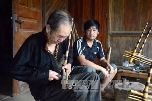 Nghệ nhân làm khèn Giàng A Sử đang truyền dạy nghề làm khèn cho con trai mình. Ảnh: Văn Dũng - TTXVN