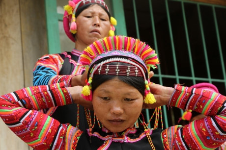 Người La Hủ hay còn gọi là Xá Lá Vàng, Cò Xung, Khù Sung, Khả Quy... hiện có khoảng 10.000 người, sinh sống chủ yếu ở đầu nguồn sông Đà, thuộc huyện Mường Tè, tỉnh Lai Châu. Tuy cuộc sống còn nhiều khó khăn, song đồng bào La Hủ nơi đây vẫn chú trọng gìn giữ bản sắc văn hóa truyền thống, nhất là phụ nữ mặc áo dài tà đen làm nổi bật vóc dáng. Phơ cơ zỡ – tiếng La Hủ có nghĩa là áo dài. Người La Hủ ở Mường Tè thường mặc áo dài tà đen. Các họa tiết, hoa văn... trên mỗi bộ trang phục phụ nữ La Hủ nói lên sự gắn bó giữa cơ thể con người trong sự vận động của cuộc sống với thiên nhiên. Áo dài của người La Hủ ngoài việc mặc ôm sát làm nổi bật đường cong của cơ thể người phụ nữ, còn đẹp ở cách phối màu sắc, cách trang trí và kỳ công của người làm. Mỗi người con gái La Hủ khi đến tuổi thành niên đều tự ý thức may cho mình một chiếc áo dài. Con gái La Hủ thường mặc loại áo cánh tay có nhiều sắc đỏ thể hiện sức sống tươi trẻ và niềm tin yêu cuộc sống. Do hoàn toàn được làm thủ công, nên thời gian để người La Hủ may một chiếc áo dài có khi mất cả tháng mới xong. Duyên dáng thiếu nữ dân tộc La Hủ. Cao nhất trên đầu là vành khăn trang trí với 5 màu sắc. Khăn quấn đầu chủ yếu được làm bằng vải đủ màu và hạt cườm rủ xuống, tạo nét khả ái cho khuôn mặt của người phụ nữ. Để có được bộ trang phục, khăn đội đầu đẹp, đòi hỏi ý tưởng sáng tạo nghệ thuật của người làm. Màu sắc chủ đạo được phối ở cánh tay và điểm xuyết bạc trắng ở thân áo. Làm đẹp cho thân áo còn có sự kết hợp của các hoa văn làm bằng nhôm hình tròn, hình tam giác. Một chiếc áo đẹp còn ở cách trang trí, bài trí những đường diềm tỉ mỉ trên thân áo, tay áo nổi bật lên trên nền vải đen với nhiều màu chỉ đen, đỏ, vàng... May tay áo là công đoạn chiếm nhiều thời gian nhất, có thể tận dụng vải cũ làm lớp lót bên trong, phía ngoài được may ngược. Một ngày với người phụ nữ La Hủ được bắt đầu bằng việc vận trang phục và công đoạn lâu nhất là bện tóc, bọc bằng sợi dây vải màu hồng. Mũ đội đầu Người La Hủ khâu ngực áo rất cẩn thận, đây là công đoạn tách rời những đường viền xếp chồng lên nhau của các loại vải. Việc này không chỉ thể hiện sự khéo léo của những người phụ nữ, mà còn là một trong những nét đẹp trong văn hóa truyền thống của người La Hủ. Vòng quấn đầu được làm từ cây song, mây trên rừng và được điểm tô bằng những chiếc ghim nhôm trang trí. Trang phục truyền thống dân tộc La Hủ đang có nguy cơ mai một, do những thách thức từ điều kiện kinh tế - xã hội.. ...Và việc đồng hóa giữa các dân tộc về phong tục, trang phục. Lớp trẻ dân tộc La Hủ ngày nay thường tự ti khi mặc áo dài dân tộc mình. Người La Hủ hay còn gọi là Xá Lá Vàng, Cò Xung, Khù Sung, Khả Quy... hiện có khoảng 10.000 người, sinh sống chủ yếu ở đầu nguồn sông Đà, thuộc huyện Mường Tè, tỉnh Lai Châu. Tuy cuộc sống còn nhiều khó khăn, song đồng bào La Hủ nơi đây vẫn chú trọng gìn giữ bản sắc văn hóa truyền thống, nhất là phụ nữ mặc áo dài tà đen làm nổi bật vóc dáng. Phơ cơ zỡ – tiếng La Hủ có nghĩa là áo dài. Người La Hủ ở Mường Tè thường mặc áo dài tà đen. Các họa tiết, hoa văn... trên mỗi bộ trang phục phụ nữ La Hủ nói lên sự gắn bó giữa cơ thể con người trong sự vận động của cuộc sống với thiên nhiên. Áo dài của người La Hủ ngoài việc mặc ôm sát làm nổi bật đường cong của cơ thể người phụ nữ, còn đẹp ở cách phối màu sắc, cách trang trí và kỳ công của người làm. Mỗi người con gái La Hủ khi đến tuổi thành niên đều tự ý thức may cho mình một chiếc áo dài. Con gái La Hủ thường mặc loại áo cánh tay có nhiều sắc đỏ thể hiện sức sống tươi trẻ và niềm tin yêu cuộc sống. Do hoàn toàn được làm thủ công, nên thời gian để người La Hủ may một chiếc áo dài có khi mất cả tháng mới xong. Duyên dáng thiếu nữ dân tộc La Hủ. Cao nhất trên đầu là vành khăn trang trí với 5 màu sắc. Khăn quấn đầu chủ yếu được làm bằng vải đủ màu và hạt cườm rủ xuống, tạo nét khả ái cho khuôn mặt của người phụ nữ. Để có được bộ trang phục, khăn đội đầu đẹp, đòi hỏi ý tưởng sáng tạo nghệ thuật của người làm. Màu sắc chủ đạo được phối ở cánh tay và điểm xuyết bạc trắng ở thân áo. Làm đẹp cho thân áo còn có sự kết hợp của các hoa văn làm bằng nhôm hình tròn, hình tam giác. Một chiếc áo đẹp còn ở cách trang trí, bài trí những đường diềm tỉ mỉ trên thân áo, tay áo nổi bật lên trên nền vải đen với nhiều màu chỉ đen, đỏ, vàng... May tay áo là công đoạn chiếm nhiều thời gian nhất, có thể tận dụng vải cũ làm lớp lót bên trong, phía ngoài được may ngược. Một ngày với người phụ nữ La Hủ được bắt đầu bằng việc vận trang phục và công đoạn lâu nhất là bện tóc, bọc bằng sợi dây vải màu hồng. Mũ đội đầu Người La Hủ khâu ngực áo rất cẩn thận, đây là công đoạn tách rời những đường viền xếp chồng lên nhau của các loại vải. Việc này không chỉ thể hiện sự khéo léo của những người phụ nữ, mà còn là một trong những nét đẹp trong văn hóa truyền thống của người La Hủ. Vòng quấn đầu được làm từ cây song, mây trên rừng và được điểm tô bằng những chiếc ghim nhôm trang trí. Trang phục truyền thống dân tộc La Hủ đang có nguy cơ mai một, do những thách thức từ điều kiện kinh tế - xã hội.. ...Và việc đồng hóa giữa các dân tộc về phong tục, trang phục. Lớp trẻ dân tộc La Hủ ngày nay thường tự ti khi mặc áo dài dân tộc mình.