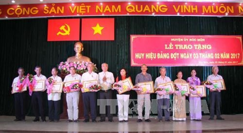 Đồng chí Nguyễn Cư, Bí thư Huyện ủy huyện Hóc Môn trao huy hiệu 65 năm tuổi đảng cho đồng chí lão thành cách mạng. Ảnh: Thanh Vũ-TTXVN
