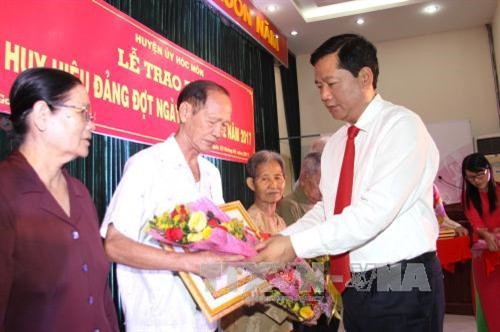 Đồng chí Đinh La Thăng, Ủy viên Bộ Chính trị, Bí thư Thành ủy Thành phố Hồ Chí Minh trao huy hiệu 70 năm tuổi đảng cho các đồng chí lão thành cách mạng. Ảnh: Thanh Vũ-TTXVN