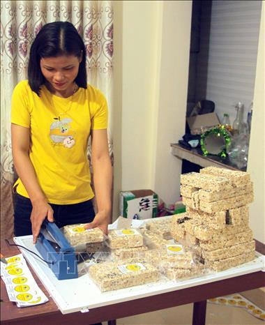 Chị Mai Thị Tuyết Sương đóng gói bánh nổ để bảo quản trước khi xuất bán. Ảnh: Trịnh Bang Nhiệm - TTXVN Chị Mai Thị Tuyết Sương đóng gói bánh nổ để bảo quản trước khi xuất bán. Ảnh: Trịnh Bang Nhiệm - TTXVN