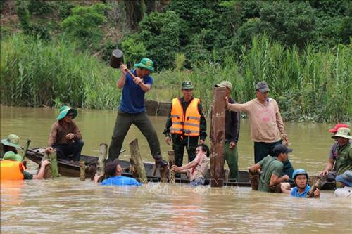 Các lực lượng chức năng cùng người dân dùng cọc và lưới sắt để làm kè đoạn đê bị vỡ. Ảnh: Tuấn Anh – TTXVN