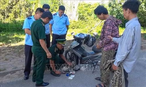 Lực lượng chức năng kiểm tra xe máy của đối tượng Lò Văn Sáng (áo ca rô). Ảnh: TTXVN phát