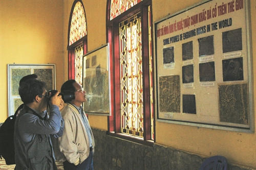 Du khách quan tâm tới các hình khắc, nét chữ được chụp lại ở bãi đá cổ sa Pa