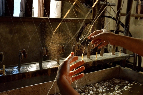 Đôi bàn tay khéo léo kéo những sợi tơ từ kén tằm.