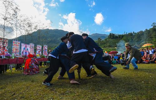 Bàn thờ treo bộ tranh thờ “Tam thanh” - 3 vị thần trong tín ngưỡng người Dao cai quản 3 nơi là Ngọc thanh (thần cai quản trên trời), Thượng thanh (thần cai quản trần gian) và Thái thanh (thần cai quản âm phủ). Theo truyền thuyết, tuy là vua nhưng Bàn Vương vẫn giữ thói quen sống giản dị, gần gũi với thiên nhiên. Ngài luôn căn dặn các con phải chăm chỉ lao động sản xuất. Có một lần, Bàn Vương cùng tùy tùng lên núi săn bắn, đuổi theo một con sơn dương bị thương, chẳng may bị sơn dương húc, ngài ngã vào cây gù hương và mất tại đó. Thi thể Bàn Vương bị vướng trên nhành cây, các con bèn chặt cây làm thân trống, đuổi bắt con sơn dương để lấy da làm trống tế lễ Bàn Vương. Từ đó. cứ đến khoảng tháng 2 Âm lịch hàng năm, con cháu người Dao từ đời này sang đời khác phải nhớ ngày cúng giỗ Bàn Vương, thể hiện sự biết ơn với tổ tiên đã sinh ra họ. Người dân các thôn chuẩn bị lễ vật, chờ đến giờ tốt để dâng lên Bàn Vương. Các thầy cúng bắt đầu thay lễ phục, giúp nhau sửa soạn mũ áo. Chân dung một trong số sáu thầy cúng của buổi lễ. Ông Triệu Chòi Quyên, thầy cúng trong xã, cho biết: "Các thầy cúng sẽ hát những bài ca cúng để nhờ thần linh, thổ địa nghênh đón Bàn Vương xuống đàn, nhận lễ vật của con cháu dâng lên". Sau mỗi lời khấn bằng tiếng Dao, thầy cúng và người dân các thôn cùng quỳ lạy Bàn Vương. Các điệu múa chuông, múa bắt rùa... lần lượt được các thầy cúng thực hiện sau khi mời để tái hiện lại tiểu sử của Bàn Vương năm xưa như vóc dáng, cách hái lượm săn bắn. Việc này theo các thầy cúng vừa để thể hiện ý chí, sức mạnh sinh tồn của người xưa, vừa để nhắc nhở con cháu ngày nay cần cù, chịu khó làm ăn như cha ông trước đây. Theo ông Quyên, vật chày là một trò chơi dân gian thể hiện sức mạnh, sự kết hợp khéo léo, sự bí ẩn của cả người gánh và người vật. Sau khi thầy cúng làm phép nhờ thần linh giúp đỡ, dù rất đông người cùng tham gia nhưng không thể ấn nổi đầu chày chạm đất. Điều này thể hiện việc bản làng năm đó được các vị thần phù hộ, nâng đỡ. Người dân tới dâng lễ và tham gia lễ hội Bàn Vương. Bàn thờ treo bộ tranh thờ “Tam thanh” - 3 vị thần trong tín ngưỡng người Dao cai quản 3 nơi là Ngọc thanh (thần cai quản trên trời), Thượng thanh (thần cai quản trần gian) và Thái thanh (thần cai quản âm phủ). Theo truyền thuyết, tuy là vua nhưng Bàn Vương vẫn giữ thói quen sống giản dị, gần gũi với thiên nhiên. Ngài luôn căn dặn các con phải chăm chỉ lao động sản xuất. Có một lần, Bàn Vương cùng tùy tùng lên núi săn bắn, đuổi theo một con sơn dương bị thương, chẳng may bị sơn dương húc, ngài ngã vào cây gù hương và mất tại đó. Thi thể Bàn Vương bị vướng trên nhành cây, các con bèn chặt cây làm thân trống, đuổi bắt con sơn dương để lấy da làm trống tế lễ Bàn Vương. Từ đó. cứ đến khoảng tháng 2 Âm lịch hàng năm, con cháu người Dao từ đời này sang đời khác phải nhớ ngày cúng giỗ Bàn Vương, thể hiện sự biết ơn với tổ tiên đã sinh ra họ. Người dân các thôn chuẩn bị lễ vật, chờ đến giờ tốt để dâng lên Bàn Vương. Các thầy cúng bắt đầu thay lễ phục, giúp nhau sửa soạn mũ áo. Chân dung một trong số sáu thầy cúng của buổi lễ. Ông Triệu Chòi Quyên, thầy cúng trong xã, cho biết: "Các thầy cúng sẽ hát những bài ca cúng để nhờ thần linh, thổ địa nghênh đón Bàn Vương xuống đàn, nhận lễ vật của con cháu dâng lên". Sau mỗi lời khấn bằng tiếng Dao, thầy cúng và người dân các thôn cùng quỳ lạy Bàn Vương. Các điệu múa chuông, múa bắt rùa... lần lượt được các thầy cúng thực hiện sau khi mời để tái hiện lại tiểu sử của Bàn Vương năm xưa như vóc dáng, cách hái lượm săn bắn. Việc này theo các thầy cúng vừa để thể hiện ý chí, sức mạnh sinh tồn của người xưa, vừa để nhắc nhở con cháu ngày nay cần cù, chịu khó làm ăn như cha ông trước đây. Theo ông Quyên, vật chày là một trò chơi dân gian thể hiện sức mạnh, sự kết hợp khéo léo, sự bí ẩn của cả người gánh và người vật. Sau khi thầy cúng làm phép nhờ thần linh giúp đỡ, dù rất đông người cùng tham gia nhưng không thể ấn nổi đầu chày chạm đất. Điều này thể hiện việc bản làng năm đó được các vị thần phù hộ, nâng đỡ. Người dân tới dâng lễ và tham gia lễ hội Bàn Vương.