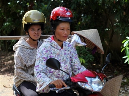 Phụ nữ dân tộc vùng cao vẫn giữ truyền thống búi tóc cao và khi đội mũ bảo hiểm sẽ rất khó khăn. (Ảnh: CTV Xuân Phúc)