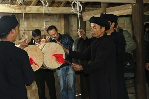 Hai người đánh trống với tư thế đứng thẳng.