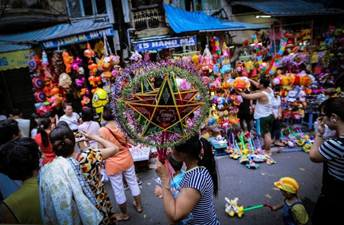 Một người phụ nữ bán những chiếc đèn ông sao thủ công lạc lõng giữa muôn ngàn những sản phẩm màu sắc sặc sỡ, trong đó hầu hết là hàng xuất xứ Trung Quốc tại phố Hàng Mã.