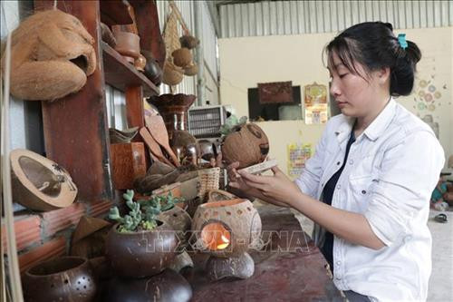 Huế My bên các sản phẩm chế tạo từ gáo dừa. Ảnh: Huỳnh Phúc Hậu - TTXVN