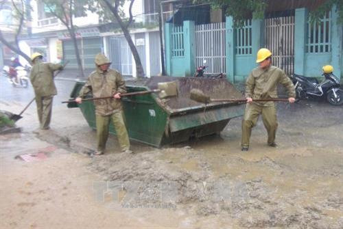 Công nhân Công ty Cổ phần Môi trường và Công trình đô thị Huế tổ chức thu gom bùn trên đường phố. Ảnh: Tường Vi - TTXVN