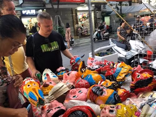 Du khách nước ngoài rất ưa thích những chiếc mặt nạ giấy bồi của hai vợ chồng nghệ nhân. Ảnh: TTXVN