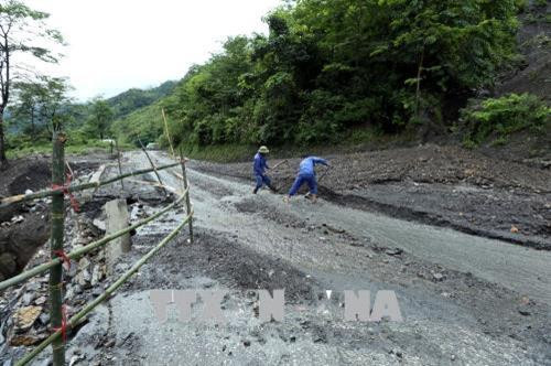 Bùn đất tràn xuống mặt đường Quốc lộ 12 gây khó khăn vất vả cho các đơn vị thi công nhằm thông tuyến giao thông. Ảnh: Phan Tuấn Anh – TTXVN