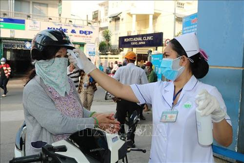 Đo thân nhiệt người đến khám bệnh tại Bệnh viện Da liễu Thành phố Hồ Chí Minh. Ảnh: Đinh Hằng – TTXVN