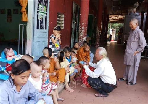 Thầy giáo Nguyễn Tiến Minh tặng quà cho các em nhỏ. Ảnh: Lê Xuân-TTXVN Thầy giáo Nguyễn Tiến Minh tặng quà cho các em nhỏ. Ảnh: Lê Xuân-TTXVN