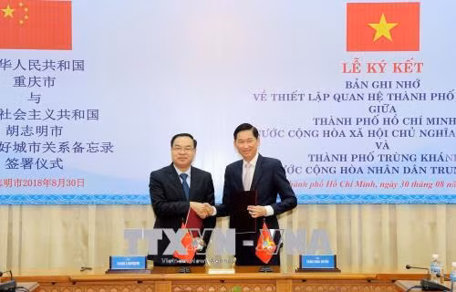 Ông Trần Vĩnh Tuyến và ông Tang Liangzhi (trái) trao đổi Biên bản thỏa thuận thiết lập quan hệ thành phố hữu nghị. Ảnh: Xuân Khu-TTXVN