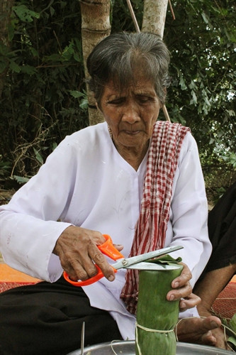 Cẩn thận cắt bỏ phần lá ở đầu để tạo cho bánh tét có hình thức đẹp trước khi đưa vào luộc. Ảnh: Chanh Đa- TTXVN