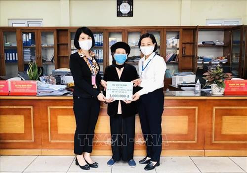 Cụ Vũ Thị Sim (103 tuổi) ủng hộ tiền phòng, chống COVID-19. Ảnh: TTXVN phát