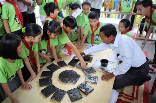 Các em học sinh thích thú với trải nghiệm làm tranh tại không gian triển lãm. Ảnh: Hồ Cầu-TTXVN