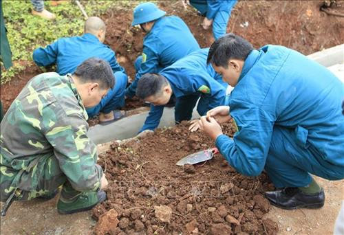 Lực lượng Dân quân tiến hành khai quật hài cốt. Ảnh: Xuân Tư - TTXVN Lực lượng Dân quân tiến hành khai quật hài cốt. Ảnh: Xuân Tư - TTXVN