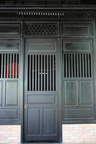 Ngôi nhà cổ được xây từ năm 1799 - Ảnh : Ngọc Tiến. Ngôi nhà được chúa Nguyễn Ánh cho xây dựng vào năm 1799 theo lối kiến trúc truyền thống của Việt Nam với ba gian, hai chái làm nơi trú ngụ cho Giám mục Bá Đa Lộc (quốc tịch Pháp, sinh năm 1741), người dạy học cho hoàng tử Nguyễn Cảnh lúc đó. Ban đầu ngôi nhà được xây dựng bên phần đất của Thảo Cầm Viên bây giờ. Năm 1911, khi Tòa Tổng Giám mục hiện nay được xây dựng hoàn thành, ngôi nhà dời về đây và được giữ gìn, bảo quản đến ngày hôm nay - Ảnh : Ngọc Tiến. Qua những lần di dời trước đó, phần nền đất làm cho cột trụ ngôi nhà bị hư hỏng. Sau đợt trùng tu nền nhà được nâng cao hơn, cột trụ ngôi nhà được đặt trên những tảng đá để đỡ một phần tải trọng và chắc chắn hơn như nguyên bản ngôi nhà ban đầu - Ảnh : Ngọc Tiến. Dàn rui lách, kèo và hệ thống vách được xếp đặt một cách tinh xảo - đó là nét độc đáo và giá trị to lớn về lịch sử và văn hóa ngôi nhà - Ảnh : Ngọc Tiến. Mái nhà được lợp ngói âm dương với những họa tiết hoa văn viền tinh xảo. Hiện nay, lớp ngói đỏ đã được làm mới thay cho lớp ngói cũ rêu phong - Ảnh : Ngọc Tiến. Các cánh cửa làm bằng gỗ quý, hoa văn được điêu khắc tinh xảo tạo thêm nét cổ kính cho mặt tiền của căn nhà - Ảnh : Ngọc Tiến. Ngôi nhà được làm hoàn toàn bằng gỗ quý, khung nhà được liên kết chặt chẽ với nhau hoàn toàn bằng kỹ thuật ghép mộng của những nghệ nhân thời xưa. Hoàn toàn không dùng bất cứ cây đinh nào nhưng ngôi nhà vẫn đứng vững qua hàng trăm năm - Ảnh : Ngọc Tiến. Các nét chạm khắc trên những bộ cửa, vách nhà chưa bị bào mòn và còn nguyên vẹn - Ảnh : Ngọc Tiến. Họa tiết trang trí được khắc họa tỉ mỉ, công phu đặt ngay cửa chính diện tạo sự cân đối và cổ kính, thể hiện nét sáng tạo độc đáo - Ảnh : Ngọc Tiến. Nhiều vật dụng trong nhà như bàn, ghế, tủ, bình phong... vẫn được giữ nguyên vẹn và còn khá tốt. Những chùm đèn được thay mới vì đèn cũ đã hư hỏng, không thể sử dụng được nữa - Ảnh : Ngọc Tiến.