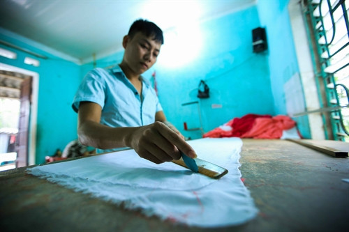 Một thợ cắt mẫu áo dài làm việc tại xưởng may Thảo Trần tại làng Trạch Xá. Một ngày, anh có thể cắt khoảng 50-60 mẫu áo. Một thợ cắt mẫu áo dài làm việc tại xưởng may Thảo Trần tại làng Trạch Xá. Một ngày, anh có thể cắt khoảng 50-60 mẫu áo.